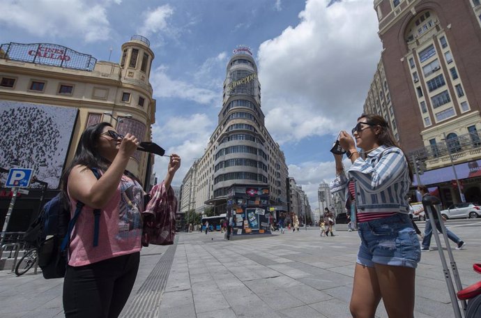 Archivo - Dos mujeres se ponen la mascarillas, después de quitársela para una foto, en la Gran Vía.