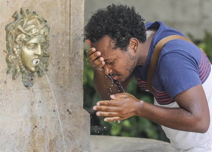 Un hombre se refresca en una fuente del centro de Valencia para soportar las altas temperaturas, a 12 de julio de 2021, en Valencia, Comunidad Valenciana (España). Las provincias de Alicante, Valencia y Murcia tienen este lunes avisos de nivel rojo (rie