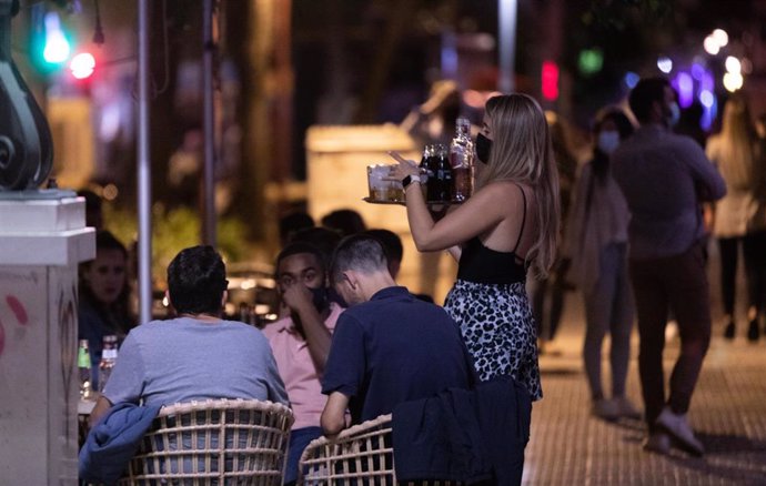 Archivo - Una camarera atiende a varias personas en la terraza de un bar de copas en la primera noche sin toque de queda tras el fin del estado de alarma, a 09 de mayo de 2021, en Sevilla (Andalucía, España). Andalucía pone fin desde este domingo, al de