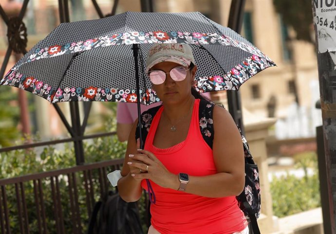 Una mujer se protege del sol con un paraguas por el calor