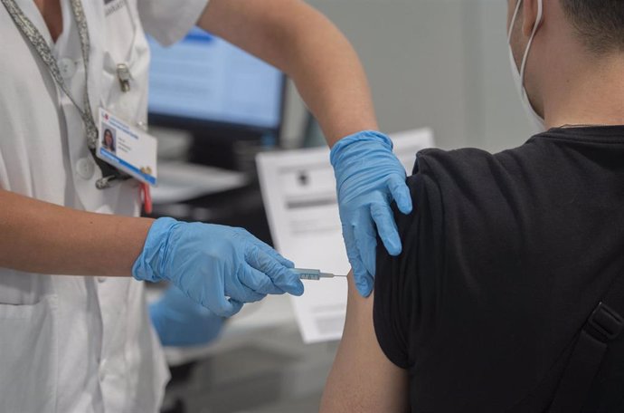Una sanitaria administra una dosis de la vacuna contra la Covid-19 a un joven