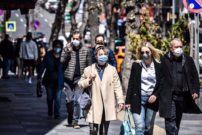 Archivo - Gente con mascarilla mientras camina por una popular calle comercial de Ankara.