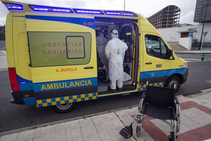 Archivo - Un trabajador sanitario totalmente protegido ayuda a subir a la ambulancia a un anciano de una residencia en Galicia.