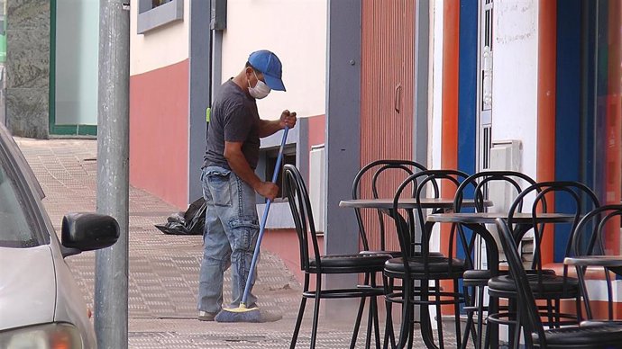Un hombre realiza tareas de limpieza con mascarilla.