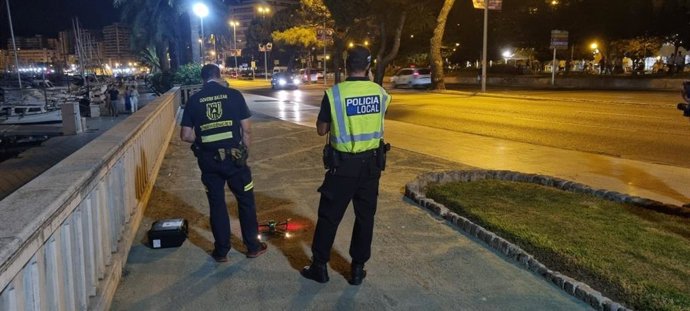 Un agente de la Policía Local y un agente de la dirección General de Emergencias del Govern junto al dron utilizado en el dispositivo antibotellón.