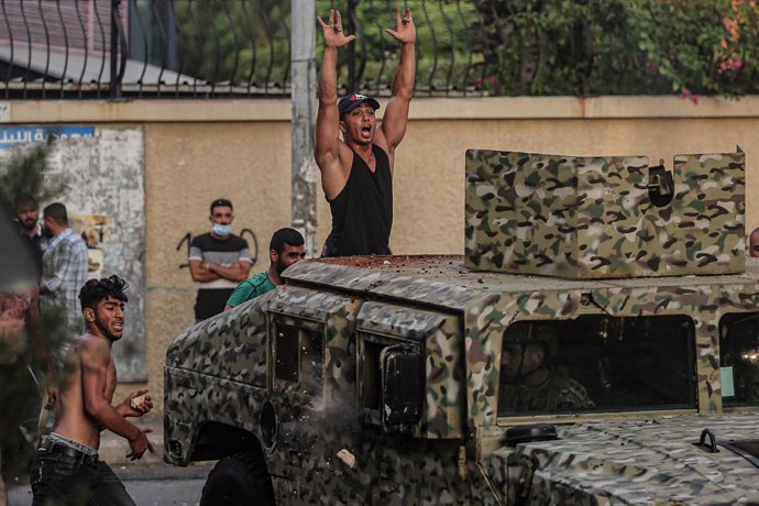 15 July 2021, Lebanon, Beirut: A protestor hurls rocks at a Lebanese army Humvee as his colleague gestures to soldiers during clashes after Lebanon's Prime Minister-designate Saad Hariri stepped down following his failure to form a government for nearly