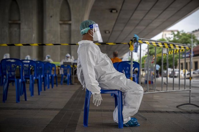 Un sanitario de Tailandia descansa mientras viste un traje de protección EPI