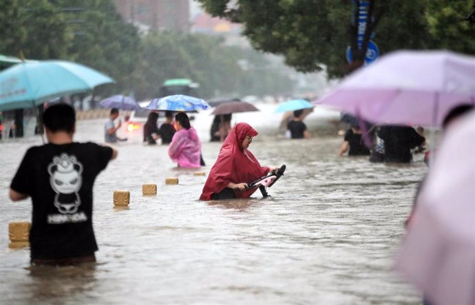 Gente camina por la carretera inundada después de lluvias récord en la ciudad de Zhengzhou, en la provincia central china de Henan.