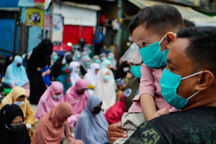 20 July 2021, Philippines, Manila: A police officer in combat uniform carries a boy as Muslims gathered outside the Manila Golden Mosque And Cultural Center for the Eid al-Adha morning prayers. Eid al-Adha is the holiest feast in Islam, during which Mus