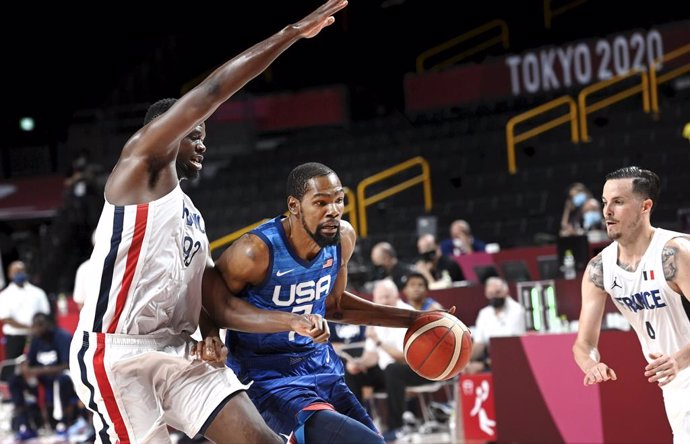 25 July 2021, Japan, Saitama: France's Moustapha Fall (L) and Thomas Heurtel (R) battle for the ball witrh USA's Kevin Durant during the Men's Preliminary Round Group A basketball match between France and the United States at the Saitama Super Arena, he