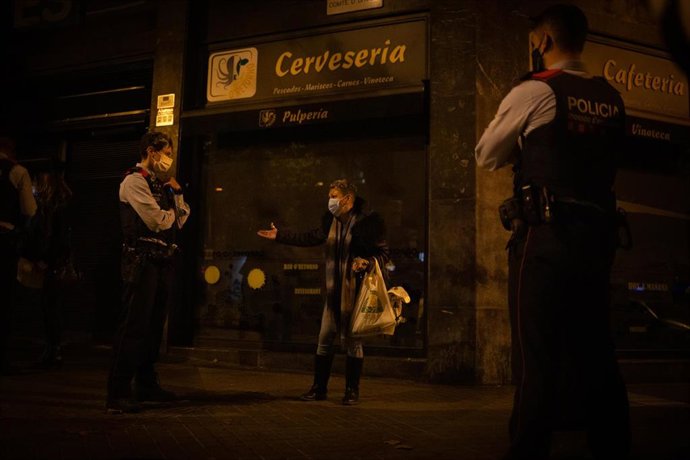 Archivo - Varios mossos d'Esquadra paran a una persona durante un control durante el toque de queda impuesto por la crisis sanitaria del Covid-19 desde las 22.00 horas a las 6.00 del día siguiente, en Barcelona, Catalunya, (España), a 6 de noviembre de 