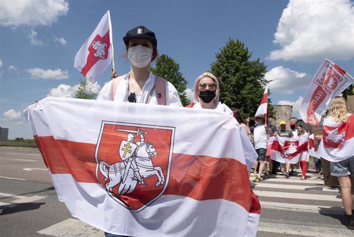 Manifestantes portan la antigua bandera bielorrusa, popularizada durante las recientes protestas contra Aleksandr Lukashenko.