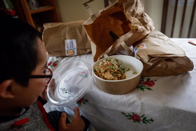 Archivo - Un niño durante la comida en su casa del barrio madrileño de Carabanchel abre la tapa de un plato del menú de la ONG del chef José Andrés