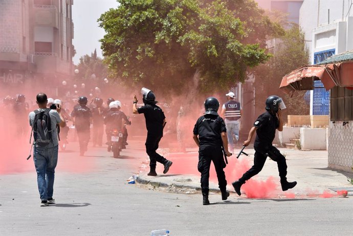 25 July 2021, Tunisia, Tunis: Tunisian security forces are enveloped by red smoke billowed by protesters during a protest against the Ennahdha party and the government on Republic Day demanding the government resign and the parliament to be dissolved. T