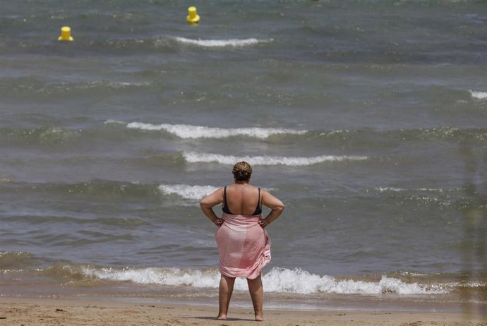 Una mujer en la Playa de la Malvarrosa en un día de alerta roja por altas temperaturas, a 12 de julio de 2021, en Valencia, Comunidad Valenciana (España). Las provincias de Alicante, Valencia y Murcia tienen este lunes avisos de nivel rojo (riesgo extre