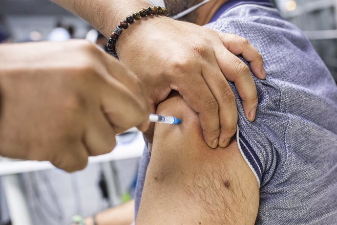 Un sanitario administra una dosis de la vacuna de Pfizer a un hombre en el Wizink Center durante la primera noche en la que el recinto está abierto a la vacunación, a 1 de julio de 2021, en Madrid (España). El centro de vacunación masiva del WiZink Cent