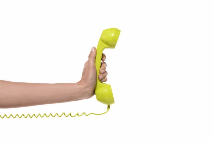Archivo - Hand holding a landline phone