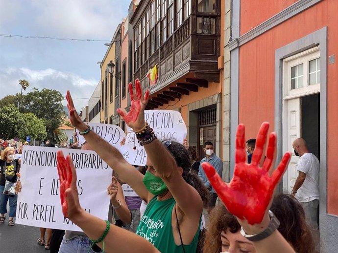 Varias personas con las manos pintadas de roja se manifiestan por los derechos de los migrantes.