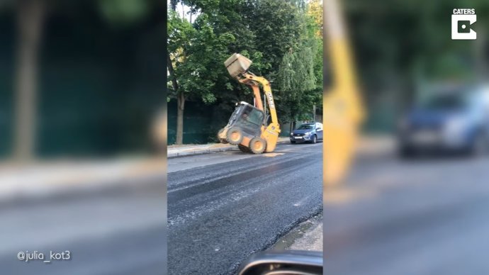 Graban a una máquina excavadora haciendo piruetas en mitad de la carretera