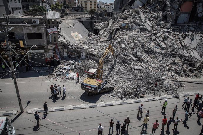Archivo - 05 June 2021, Palestinian Territories, Gaza City: Palestinians watch an excavator run by an Egyptian team clearing up the rubble of Al-Shorouk Tower that was hit and destroyed during the recent Israeli airstrikes. The Egyptian government had s