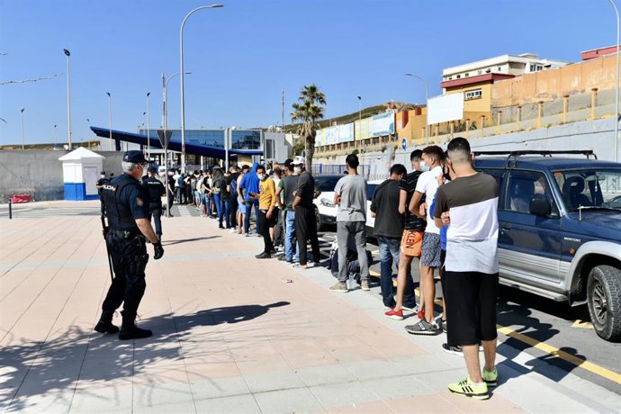 Archivo - Varios migrantes procedentes de Marruecos hacen cola en las puertas de la frontera de Ceuta donde agentes de la Policía Nacional reparten citas para solicitud de asilo, a 2 de junio de 2021, en Ceuta (España). La Policía Nacional gestionó ayer