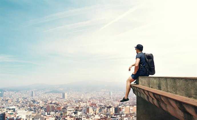 Archivo - Joven sentado en un cornisa mirando la vista a la ciudad.