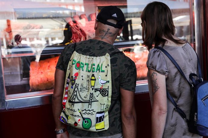 Archivo - Dos jóvenes observan uno de los comercios ubicado en el centro de Madrid.