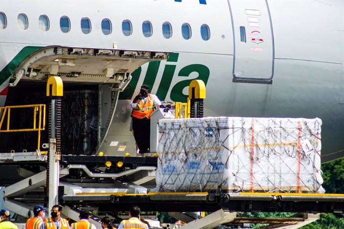 26 July 2021, El Salvador, San Luis Talpa: Logistics workers unload a shipment of the Chinese Sinovac Covid-19 vaccine at the Oscar Arnulfo Romero International Airport. El Salvador received a new shipment containing 1 million vaccine doses of the CORON