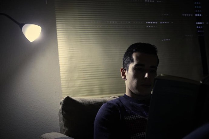 Archivo - Un joven lee bajo la luz de una lámpara.