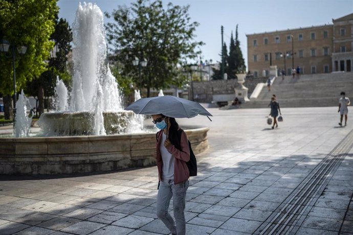 31 July 2021, Greece, Athens: A woman protects herself from the sun and heat with an umbrella in Syntagma Square amid temperatures that reached above 40 degrees. Photo: Angelos Tzortzinis/dpa