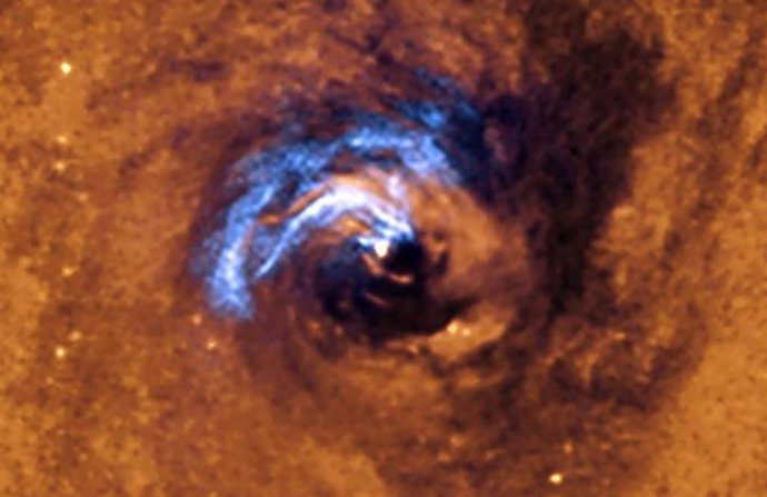 La imagen muestra el proceso de alimentación nuclear de un agujero negro en la galaxia NGC 1566, y cómo los filamentos de polvo, que rodean al núcleo activo, quedan atrapados y giran en espiral alrededor del agujero negro hasta que se los traga.