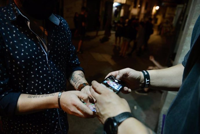 Un hombre muestra en su móvil un certificado de prueba PCR a las puertas de un local de ocio nocturno, en el centro de Ourense