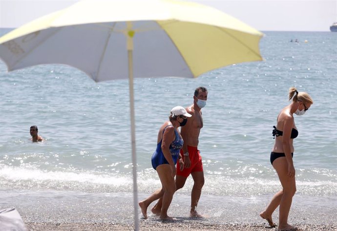 Archivo - Bañistas con mascarilla pasean por la orilla de la playa de La Malagueta en julio de 2020.