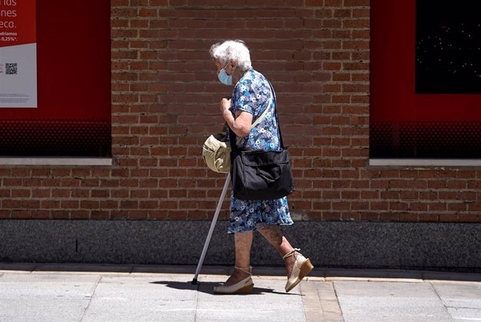 Una anciana con mascarilla camina por la calle ayudada de una muleta, a 27 de julio de 2021, en Madrid, (España).