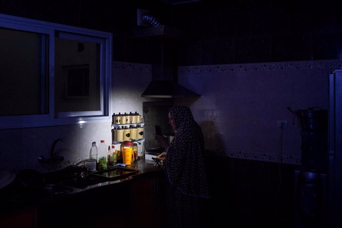 Archivo - Maha Zant hace té con la luz del teléfono celular en su casa en el distrito de Al-Zahra el 23 de julio de 2017 en Ciudad de Gaza.