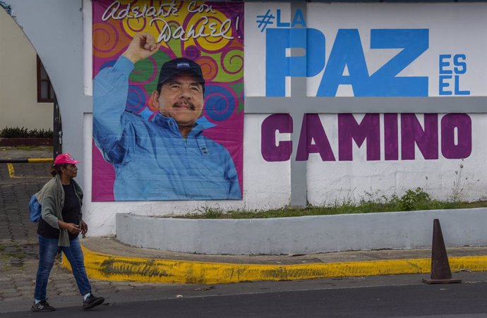 Archivo - Una mujer pasa ante un mural de Daniel Ortega en Managua