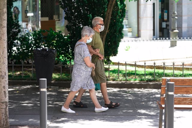 Una parella d'ancians amb mascarilla camina pel carrer agafat del braç, a 27 de juliol de 2021, a Madrid, (Espanya).