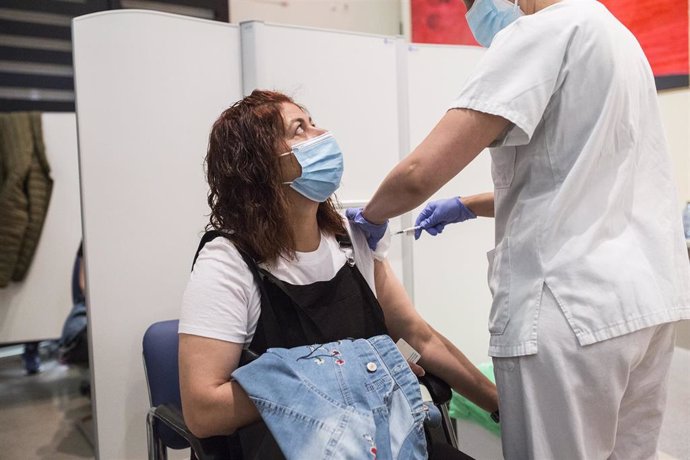 Archivo - Una sanitaria administra la primera dosis de la vacuna de Pfizer a una mujer, en el Hospital Universitario de Getafe