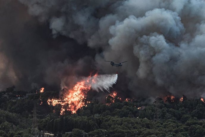  Un avión lanza agua sobre un incendio forestal declarado en una zona boscosa de Tatoi.