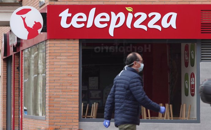 Archivo - Un hombre protegido con mascarilla pasea cerca de un local de Telepizza el mismo día en el que han comenzado a servir menús para alumnos madrileños con beca comedor y así evitar que les falten alimentos por la crisis del coronavirus.