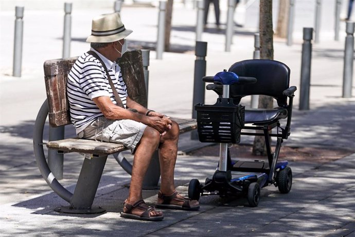 Un anciano con mascarilla sentado en un banco, a 27 de julio de 2021, en Madrid, (España).