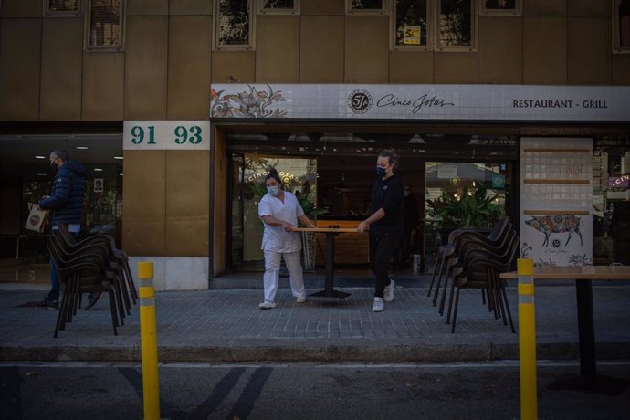 Archivo - Dos mujeres sacan una mesa a una terraza en Barcelona. 