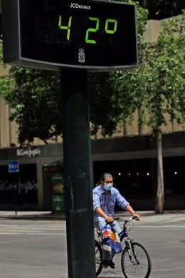 Un hombre pasea en bicicleta junto un termómetro que marca 42 durante un día de alerta roja por altas temperaturas, a 12 de julio de 2021, en la ciudad de Murcia, Murcia (España). Las provincias de Alicante, Valencia y Murcia tienen este lunes avisos d