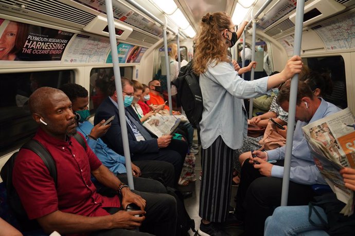 19 July 2021, United Kingdom, London: Commuters, some still wearing mouth-nose protection, sit in a Jubilee Line tube train to Westminster after the last Coronavirus measures were lifted. Despite dramatically rising infection figures, almost all Corona 