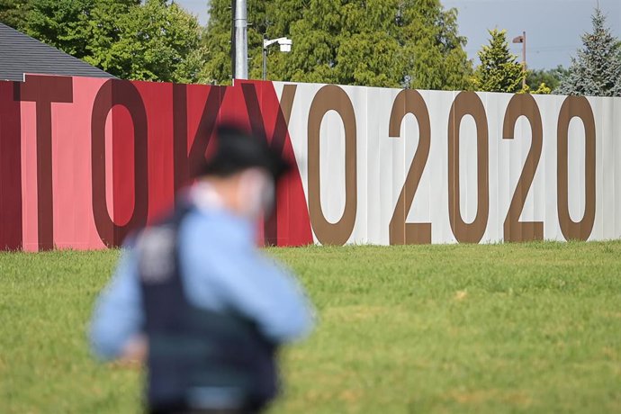 24 July 2021, Japan, Tokyo: A police officer stands in front of a 'Tokyo 2020' banner during the Tokyo 2020 Olympic Games. Photo: Sebastian Gollnow/dpa