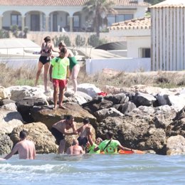 Socorristas rescatan a bañistas en una zona rocosa de la playa de Cabopino de Marbella