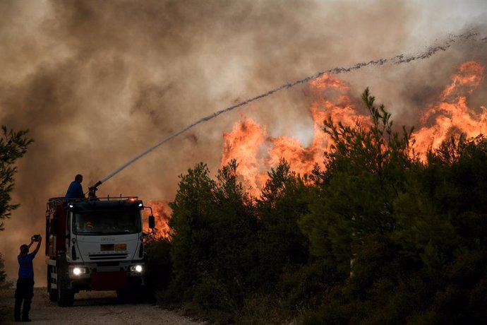 06 August 2021, Greece, Athens: Firefighters try to extinguish a forest fire in a wooded area in Agios Stefanos Avliotes village, north of Athens.  Since the early hours of the morning, strong westerly winds continued to fuel the spreading of forest fir