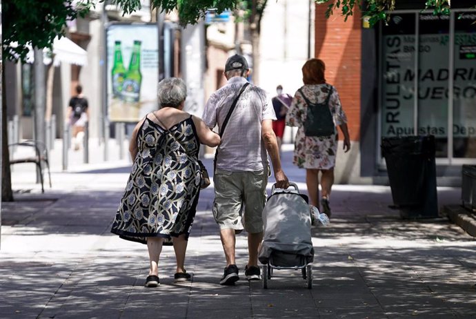 Una pareja de ancianos camina por la calle con un carro de compra, a 27 de julio de 2021, en Madrid, (España). 