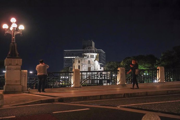 05 August 2021, Japan, Hiroshima: People take photographs of the Atomic Bomb Dome that lights up at night in the Peace Memorial Park ahead of the 76th anniversary of the atomic bombing in Hiroshima and Nagasaki by the United States during World War II. 