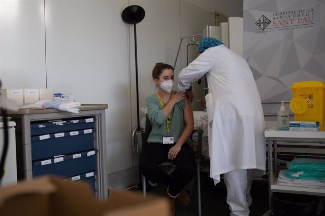Archivo - Una enfermera vacuna a un profesional sanitario con la vacuna de Pfizer-BioNtech contra el COVID-19 en el Hospital de la Santa Creu i Sant Pau de Barcelona
